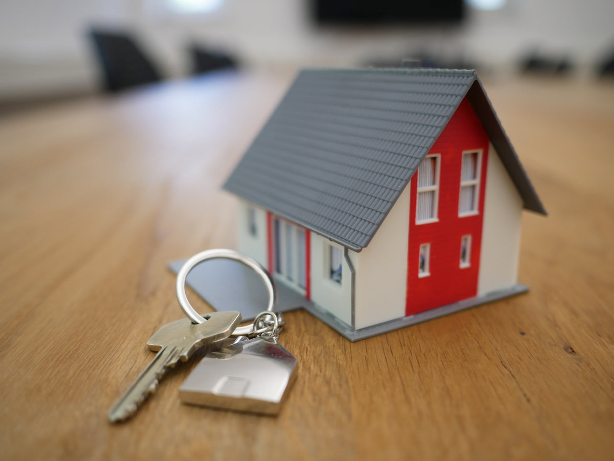 A set of keys next to a small red and white toy house